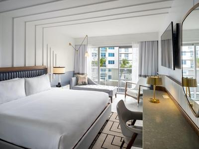 Helles, modernes Schlafzimmer mit großem Bett, Schreibtisch, Stuhl und großem Fenster mit Stadtblick.