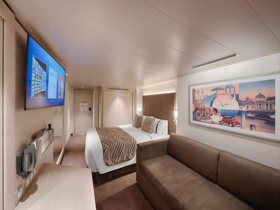 Modern eingerichtetes Hotelzimmer mit Doppelbett, TV und Sitzbereich.