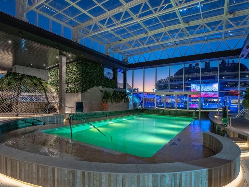 Innenpool mit beheiztem Wasser und Glasdach in einem modernen Hotel bei Abenddämmerung.