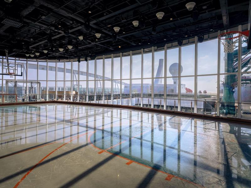 Helle Sporthalle mit großen Fenstern und Blick auf die Stadt im Hintergrund.