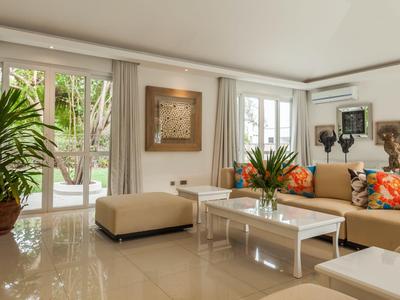 Helles Wohnzimmer mit modernen Möbeln, Glasfenstern und Pflanzen.