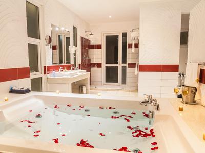 Luxuriöses Badezimmer mit Whirlpool, Rosenblättern und Kerzenlicht für entspannte Momente.