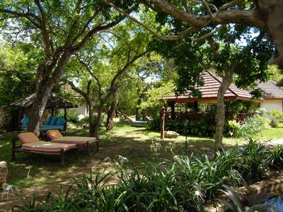 Garten mit Liegestühlen, Pavillon und üppigem Grün unter Bäumen.