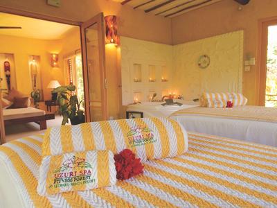 Hell eingerichteter Wellnessraum mit zwei Massageliegen und dekorativen Handtüchern.