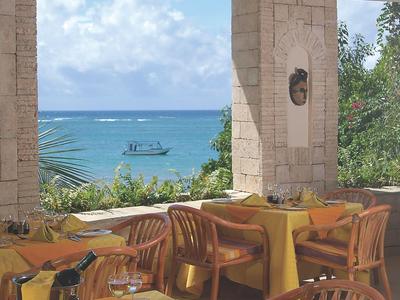 Restaurant mit Blick auf Meer und ein Boot, mit gelb gedeckten Tischen und Holzmöbeln.