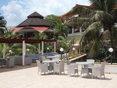 Außenbereich eines Hotels mit Sitzgelegenheiten, Pavillon und tropischen Pflanzen bei hellem Wetter