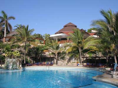Hotel mit einem großen Pool und Palmen unter klarem blauem Himmel