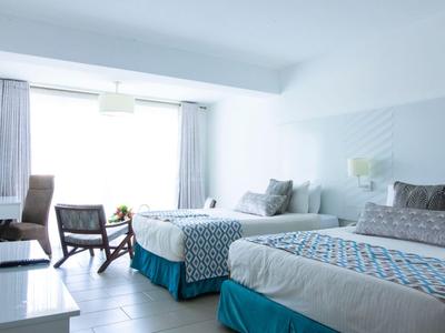 Helles Hotelzimmer mit zwei großen Betten, Stühlen und einem großen Fenster