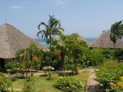 Tropisches Resort mit Strohdachbungalows und üppigem Garten unter klarem Himmel