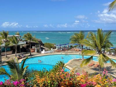 Poolbereich mit Palmen und Meerblick an einem tropischen Hotelstandort.