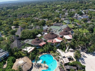 Luftaufnahme eines Resorts mit Rundhütten, Pool und Strand umgeben von tropischer Vegetation.