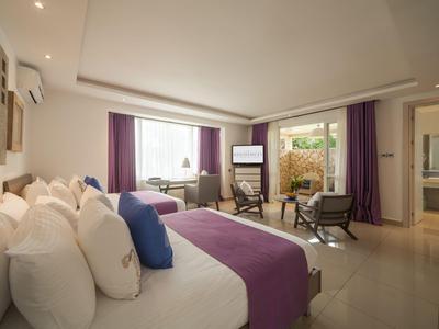 Modern eingerichtetes Hotelzimmer mit Doppelbett, Sitzbereich und großem Fenster mit Vorhängen.