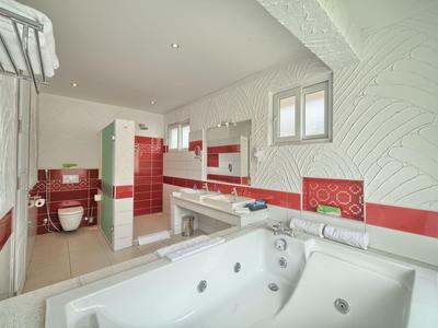 Weißes Badezimmer mit roter Fliesenverzierung, Whirlpool-Badewanne und Doppelwaschbecken