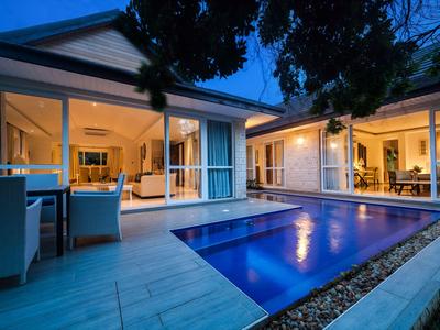 Modernes Haus mit beleuchtetem Pool und großer Terrasse bei Nacht