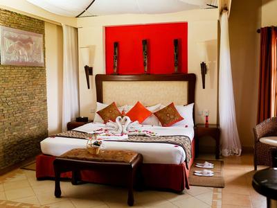 Chambre d'hôtel confortable avec lit double, mur accent rouge et espace salon.