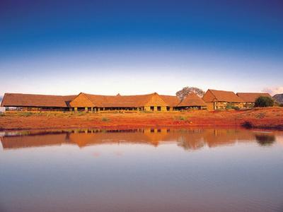 Bâtiment long au bord d'un lac calme sous un ciel clair au coucher du soleil.