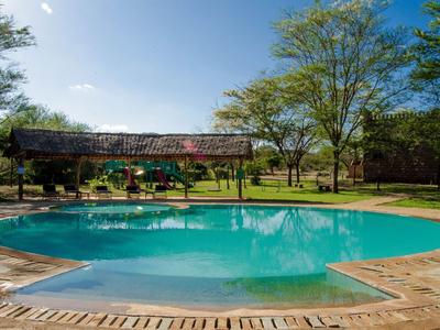 Piscine ronde avec eau turquoise, entourée de sol en pierre et d'arbres verts.
