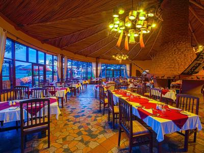 Restaurant bien éclairé avec tables dressées et grandes fenêtres en soirée.