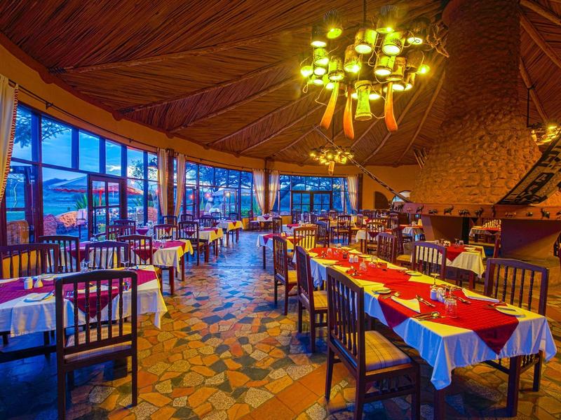 Restaurant bien éclairé avec tables dressées et grandes fenêtres en soirée.