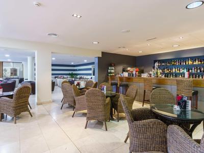 Bright hotel bar with bar area and wicker seating.