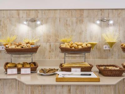 Buffet with assorted rolls and pastries against a wooden paneled wall