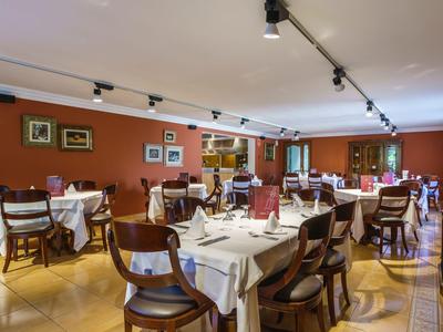 Elegantes Restaurant mit gedeckten Tischen und warmen Wänden in Orange- und Brauntönen.