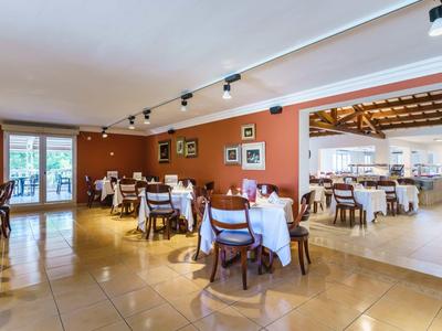 Bright restaurant with wooden chairs and white tablecloths, view of outside area.