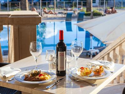 Romantisches Essen für zwei am Tisch mit Blick auf einen Pool im Freien.