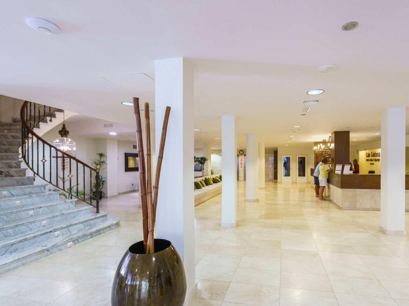 Bright hotel lobby with reception, marble floor, and a marble staircase.