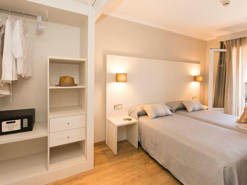 Gemütliches Hotelzimmer mit Doppelbett, Nachttischen, offener Garderobe und Balkon mit See- oder Poolblick.