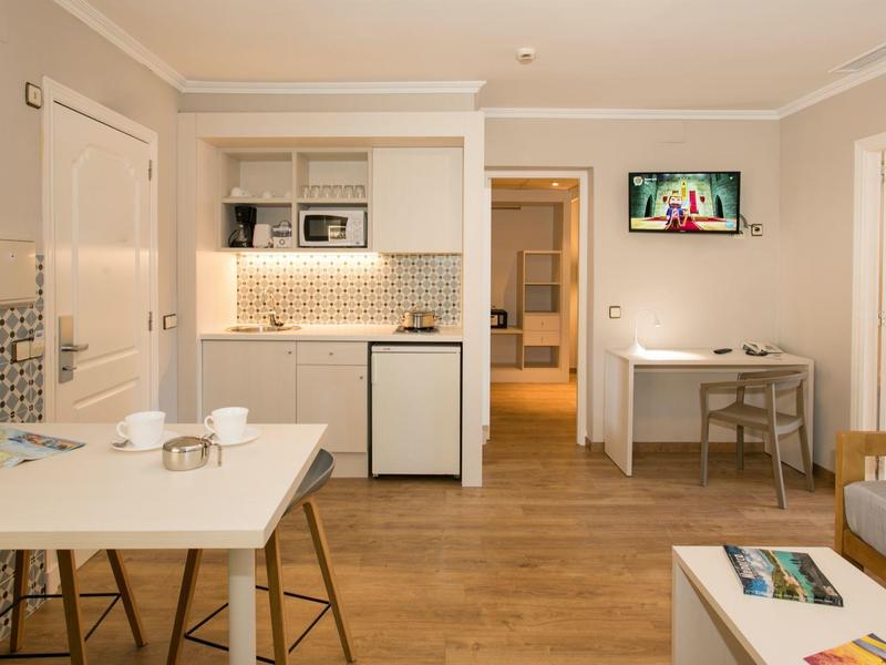 Innenraum eines modernen Hotelzimmers mit Küchenzeile und Essbereich.