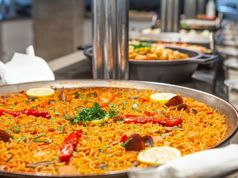 Nahaufnahme einer Pfanne mit würzigem Reisgericht und roten Chilischoten in einem Buffet.