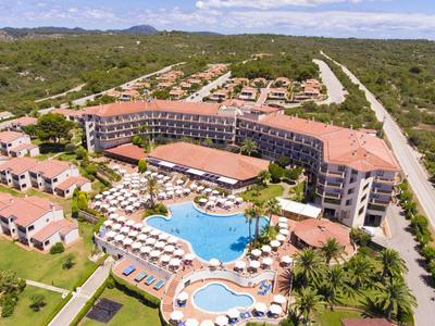 Grande resort con piscina tra la natura e diversi edifici con tetti rossi.