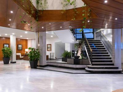 Area moderna dell'atrio dell'hotel con pavimento in marmo, scala e posti a sedere sotto un soffitto in legno.