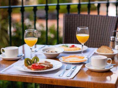 Tavolo per la colazione su una terrazza con succo, caffè, frutta e dolci.