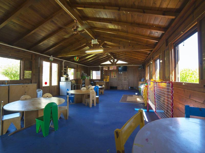 Ampia stanza luminosa con pareti in legno e mobili, perfetta per attività ricreative in hotel.