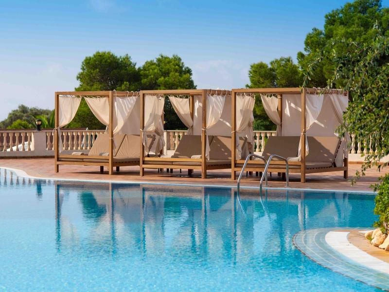 Zona piscina con quattro terrazze coperte e lettini in una giornata di sole.