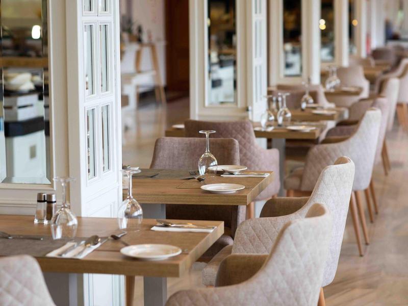 Ristorante elegante con tavoli in legno, sedie comode e curata apparecchiatura.