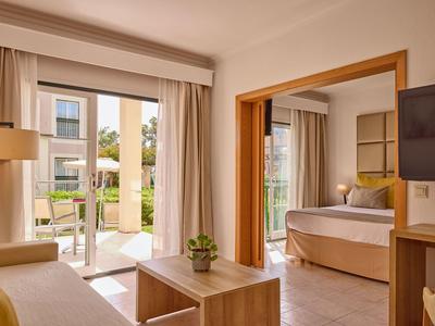Nowoczesny pokój hotelowy z balkonem, sofą i widokiem na ogród.