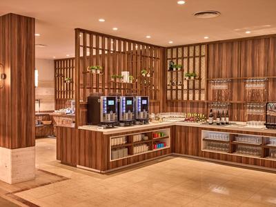Nowoczesna lobby hotelowa z ekspresami do kawy, drewnianymi panelami i jasnym oświetleniem.