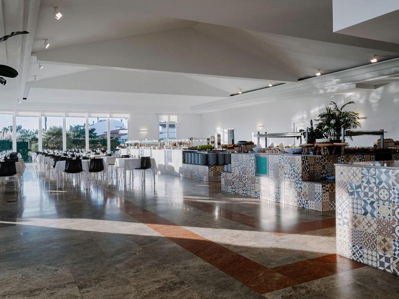 Ruime hotel lobby met patroontegels en moderne inrichting onder een wit gewelfd plafond.
