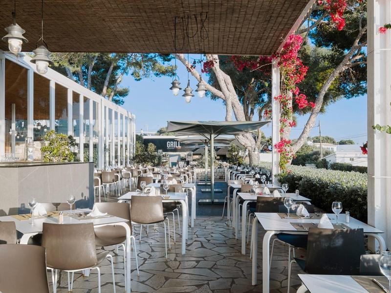 Buitenkant van een café met veel tafels en stoelen onder een overdekt terras.