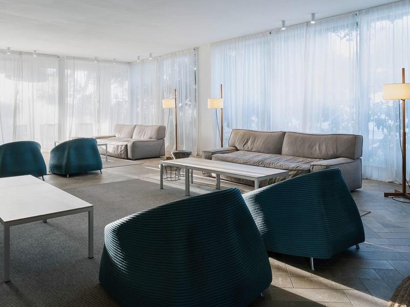 Moderne hotel loungeruimte met banken en fauteuils bij daglicht.