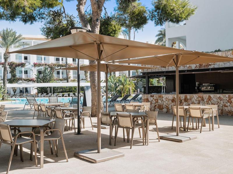 Vrijetijdsgebied in het hotel met tafels, stoelen en grote parasols bij het zwembad.