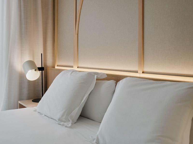 Modern hotelkamer met crème hoofdeinde en wit beddengoed