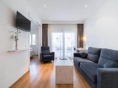 Modern living room with gray sofa, TV, and wooden floor in a hotel room.