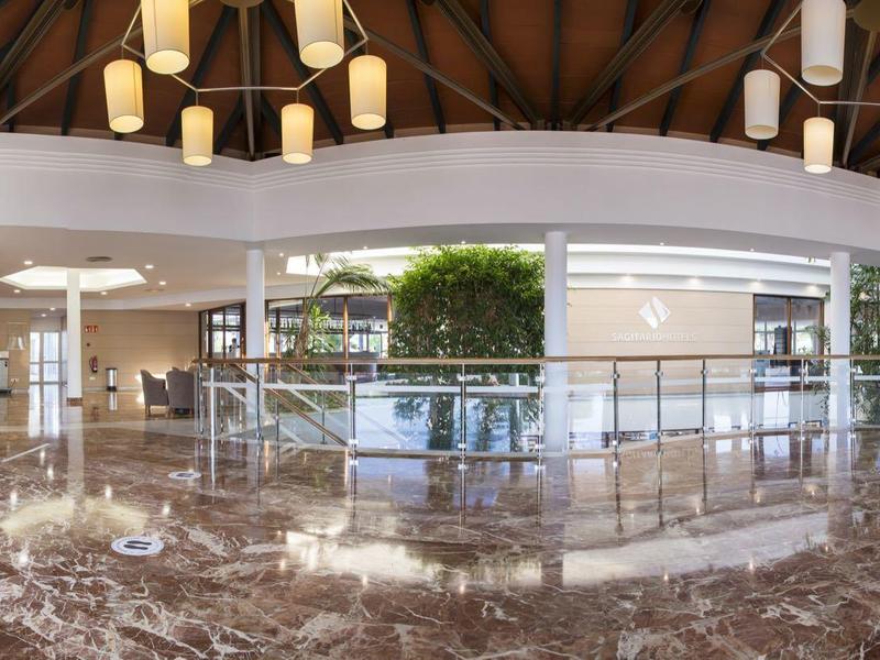 Spacious hotel lobby with polished marble floor, reception desk, and natural lighting.