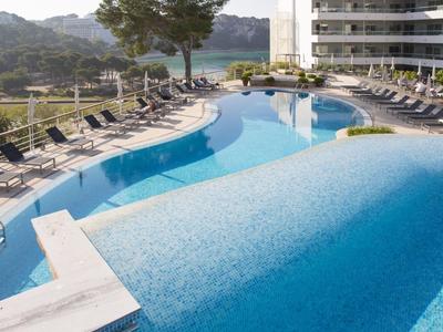 A luxurious hotel pool with sun loungers and mountain view in the background.