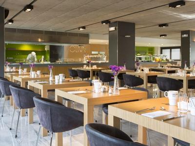 Modern restaurant interior with wooden tables, black chairs, and minimalist decor.