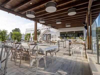Spacious outdoor dining area with tables, chairs, and wooden ceiling under shaded roof.